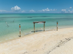 A beach with a wooden structure, clear turquoise water, and a sign reading "South Tulum Bay Eleutheria". - Hilton's Haven (Tarpum Bay)