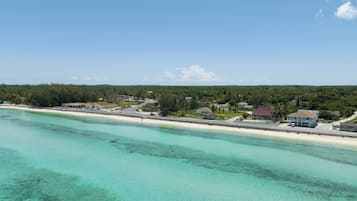 Une zone côtière dotée d’une plage, d’eaux turquoise et limpides, et d’immeubles résidentiels.