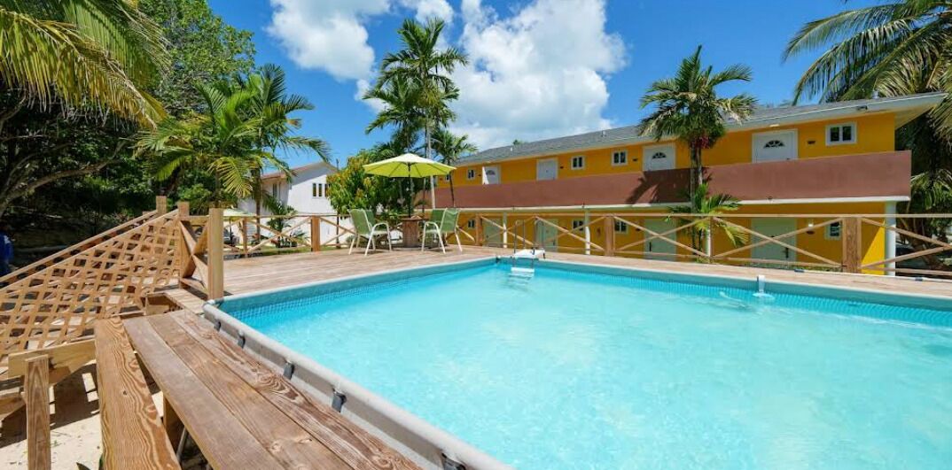 A clear blue pool with wooden deck seating and a wooden fence.