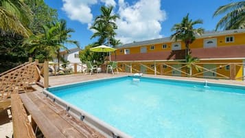 A clear blue pool with wooden deck seating and a wooden fence.