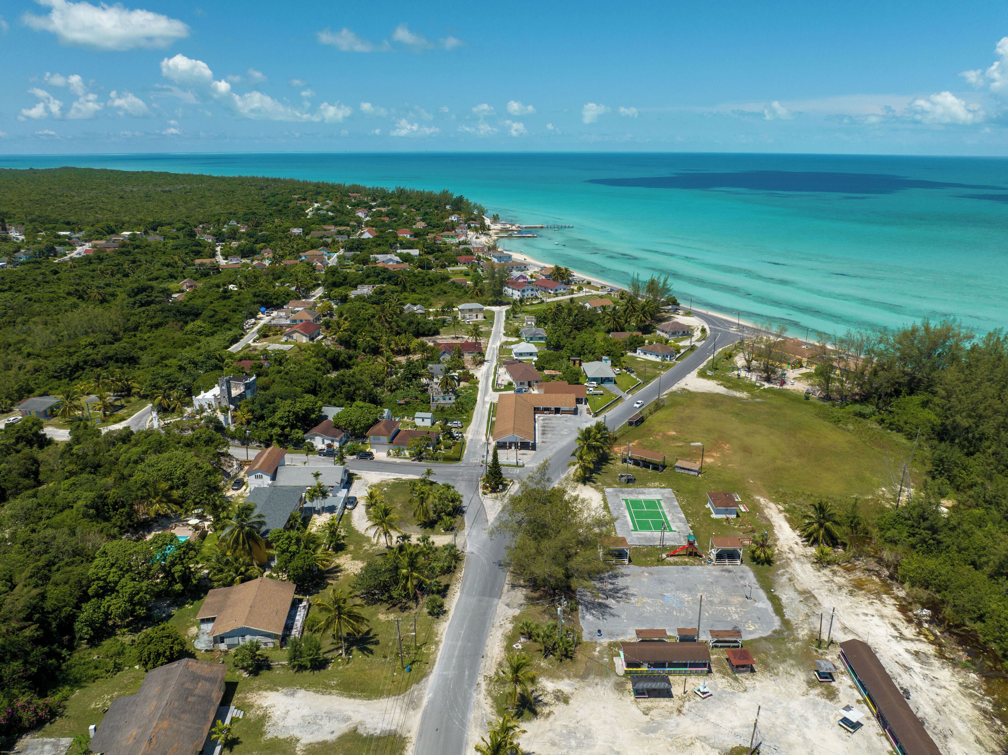 Vue aérienne d’une zone résidentielle côtière, avec des maisons, une route et une plage.