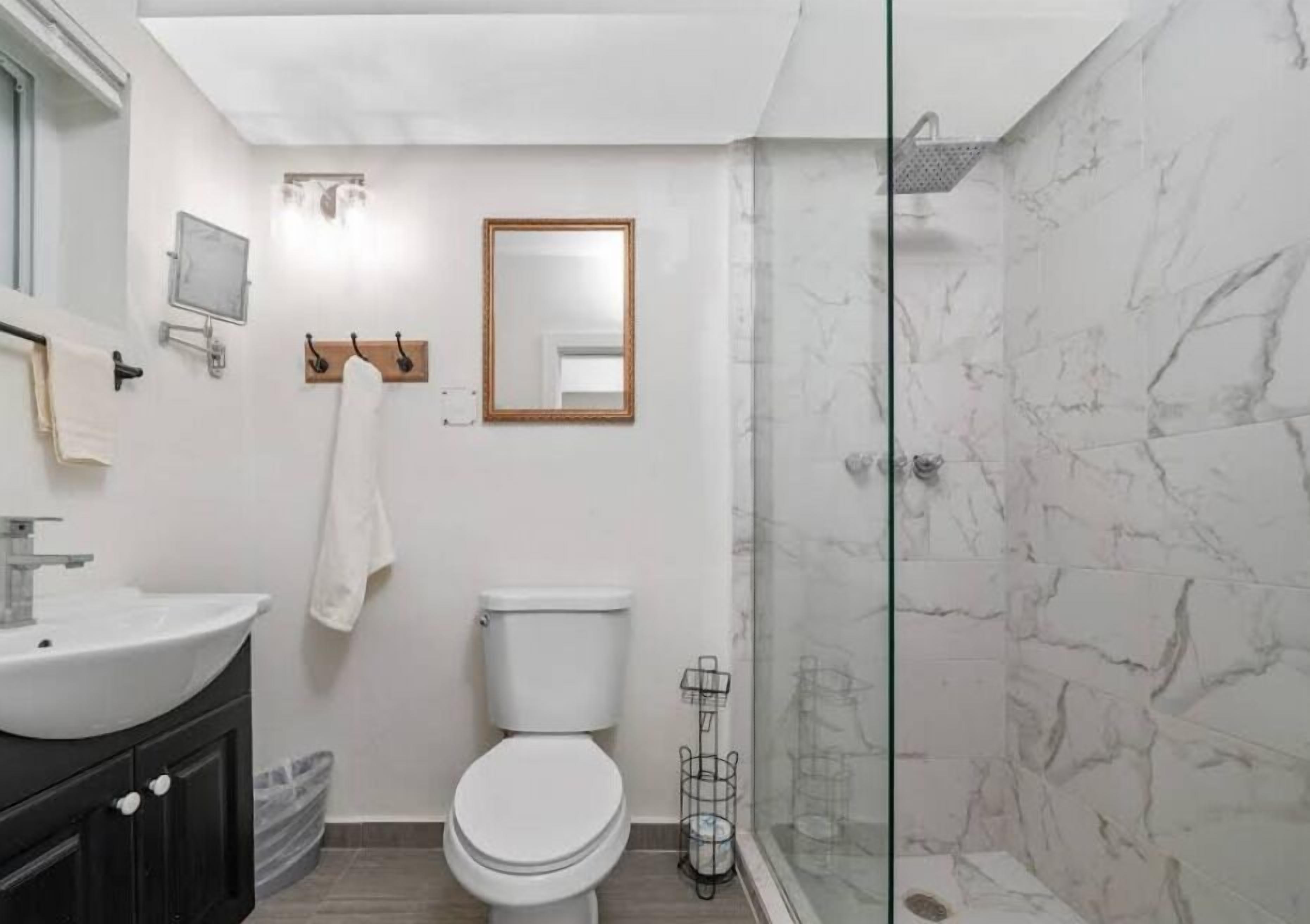 A bathroom with a white sink, toilet, and glass shower enclosure.