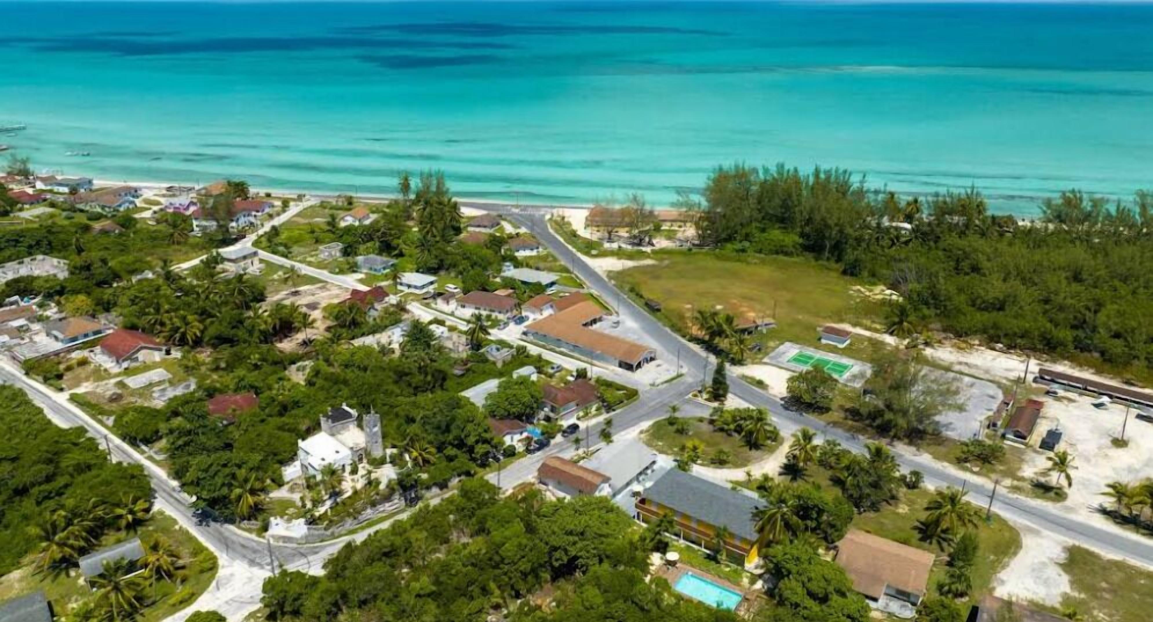 Vista aérea de una zona residencial costera con casas, carreteras y una playa.
