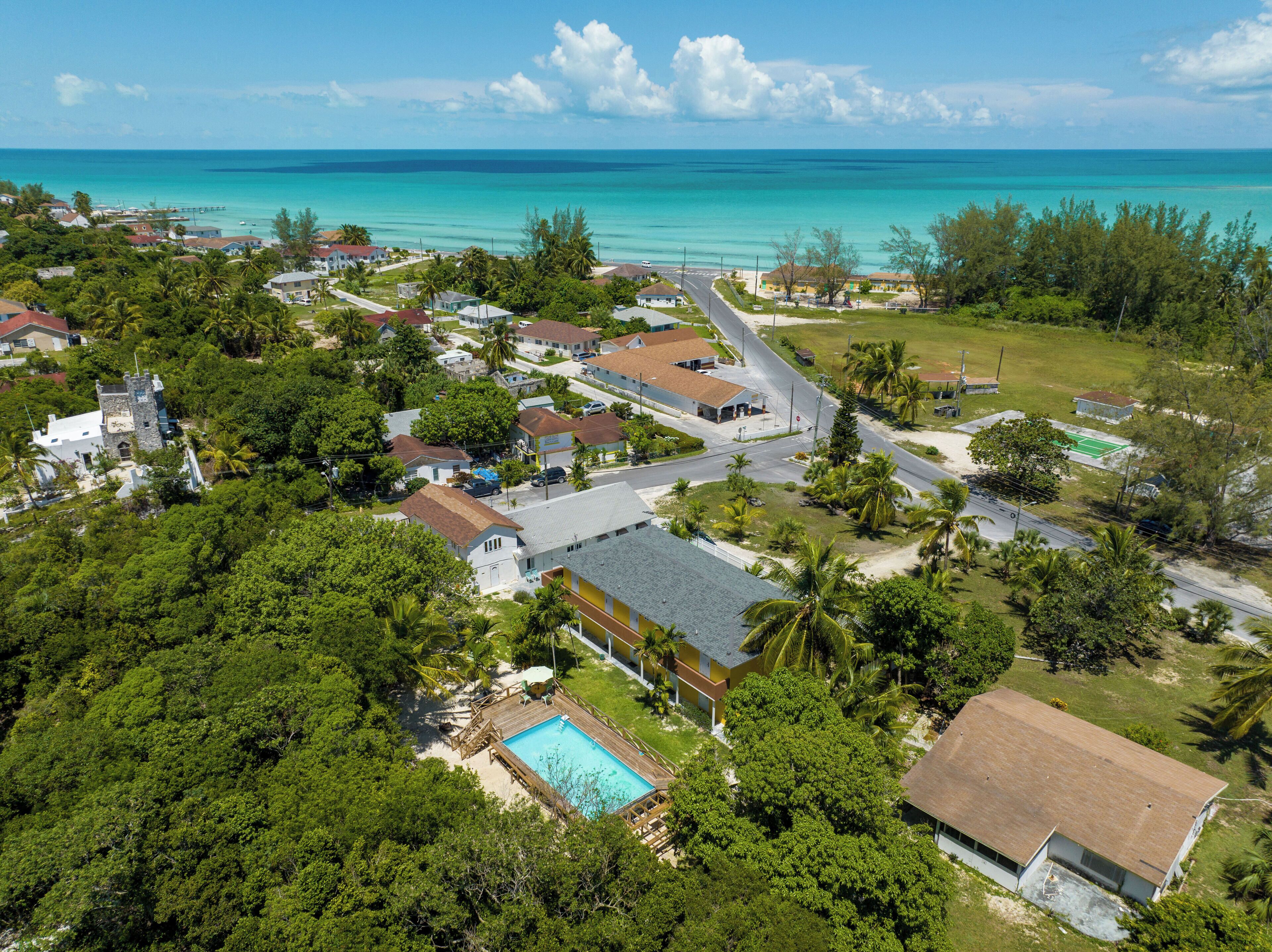 Vue aérienne d’un quartier résidentiel situé sur la côte, avec des maisons, une piscine et une plage.