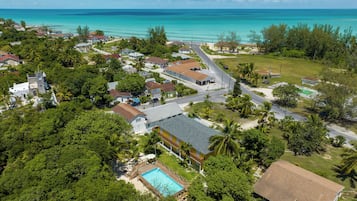 Vue aérienne d’un quartier résidentiel situé sur la côte, avec des maisons, une piscine et une plage.