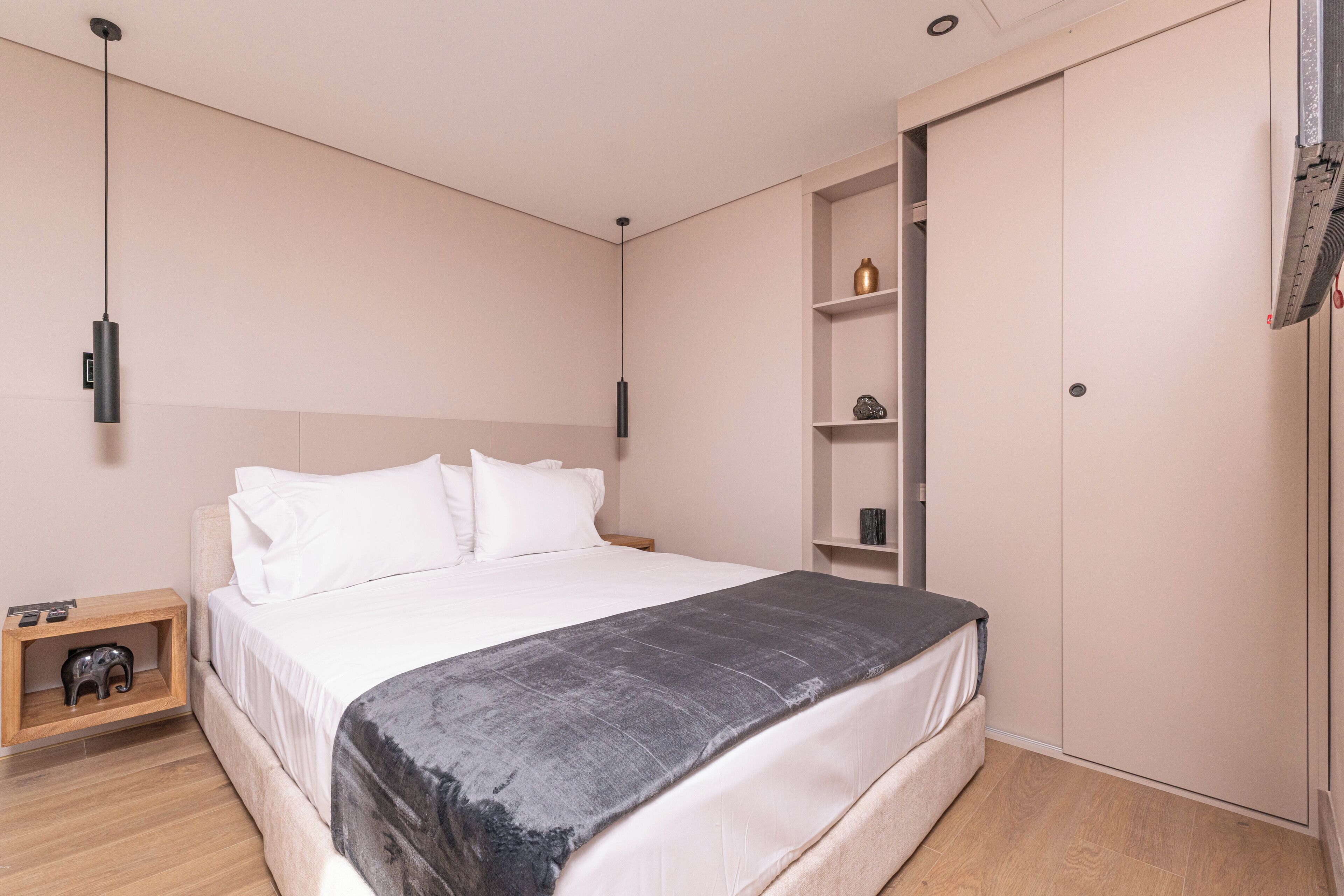 A modern bedroom with a bed, bedside tables, a wardrobe, and a shelf unit.