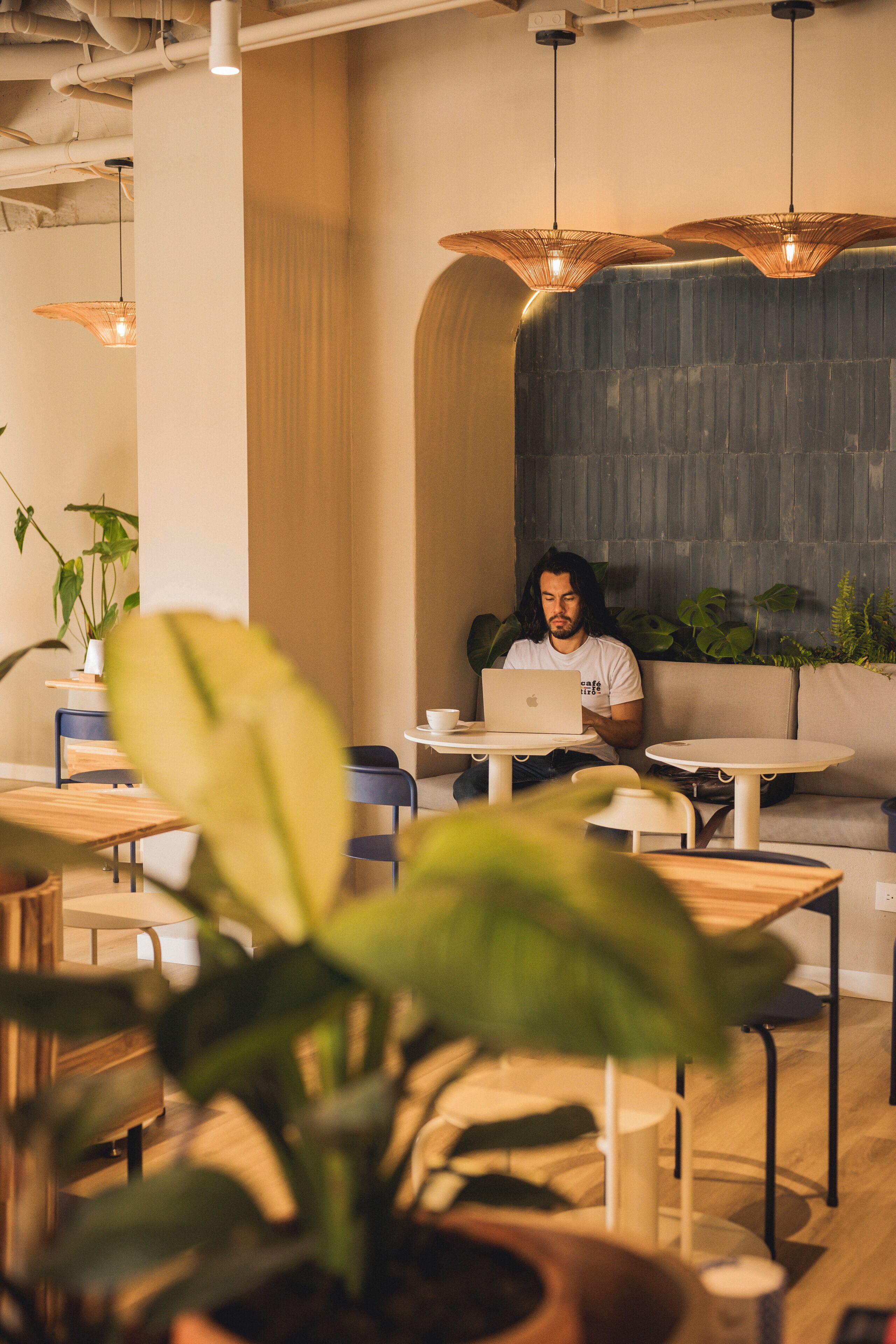 A modern cafe interior with a person using a laptop at a table.