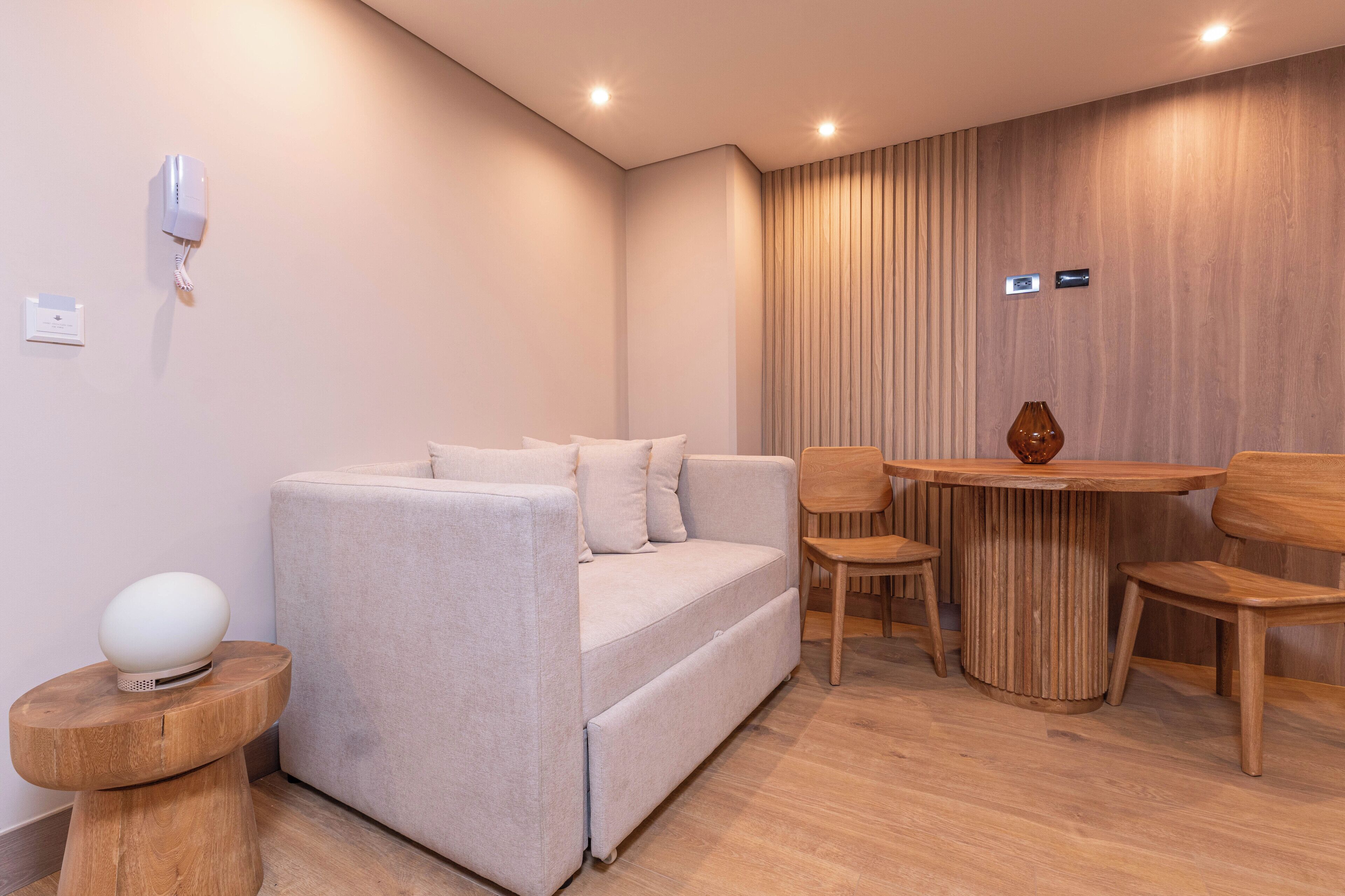 A modern living room with a sofa, a round wooden table, and two chairs.