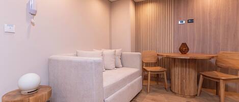 A modern living room with a sofa, a round wooden table, and two chairs.