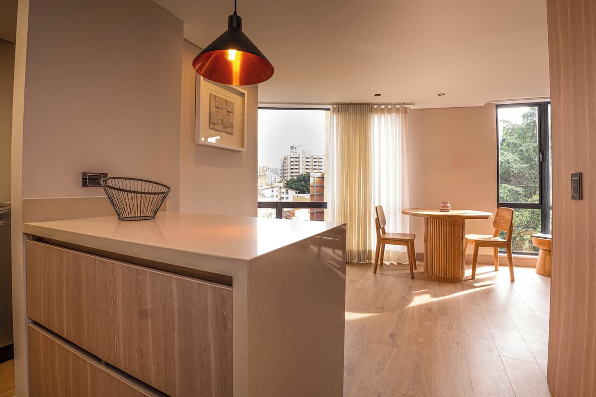 Une cuisine moderne avec un plan de travail en bois, un luminaire suspendu et une vue sur la ville grâce à de grandes fenêtres.