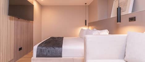 Une chambre d’hôtel moderne équipée d’un lit, d’un canapé, d’un téléviseur à écran plat et d’un climatiseur fixé au mur.