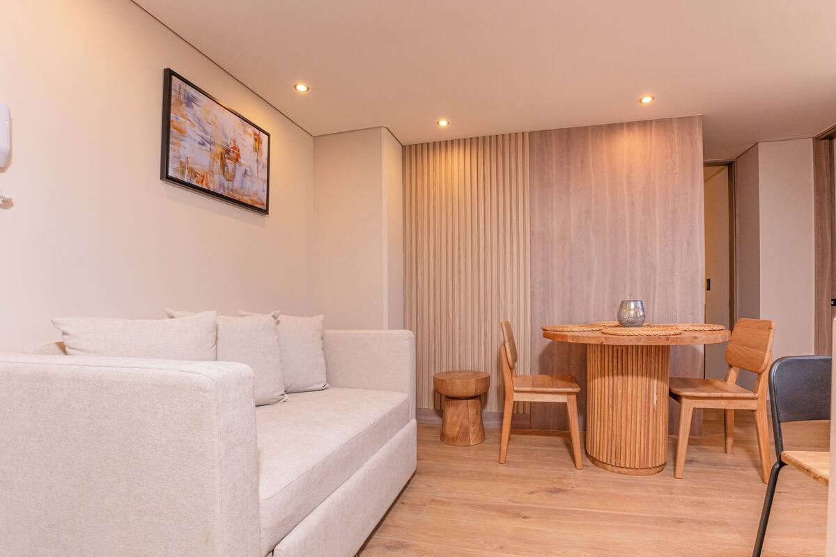 Un salon moderne avec un canapé, une table à manger en bois et des chaises.