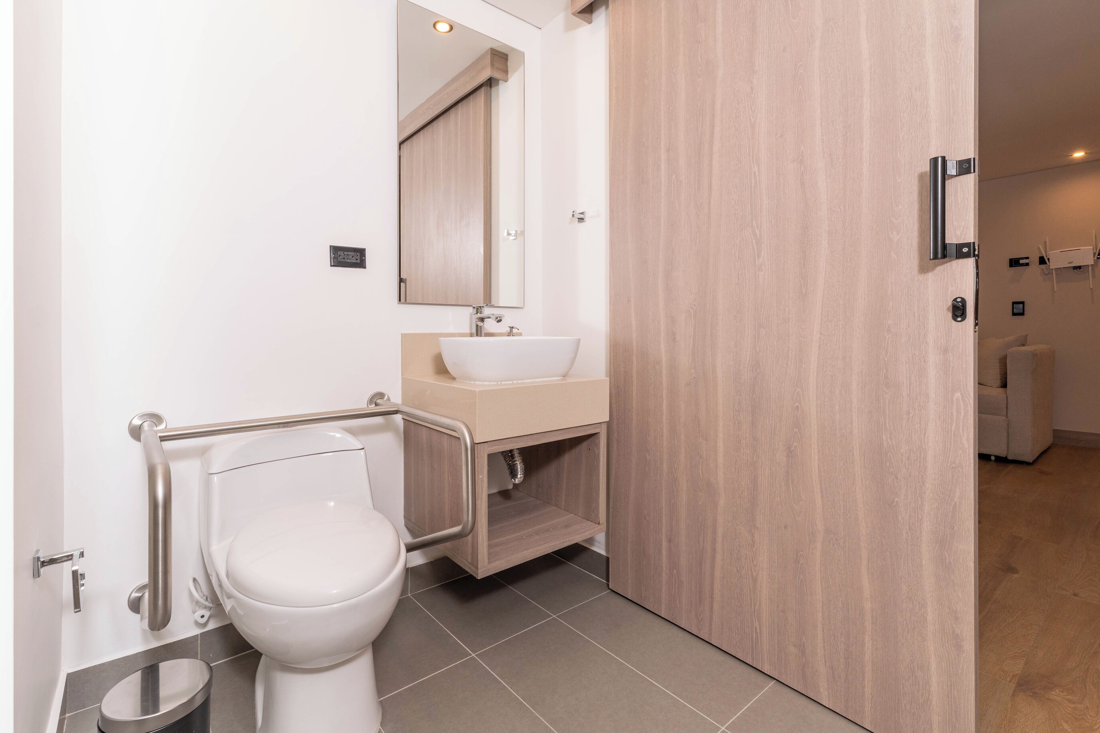 A modern bathroom with a toilet, sink, and mirror.