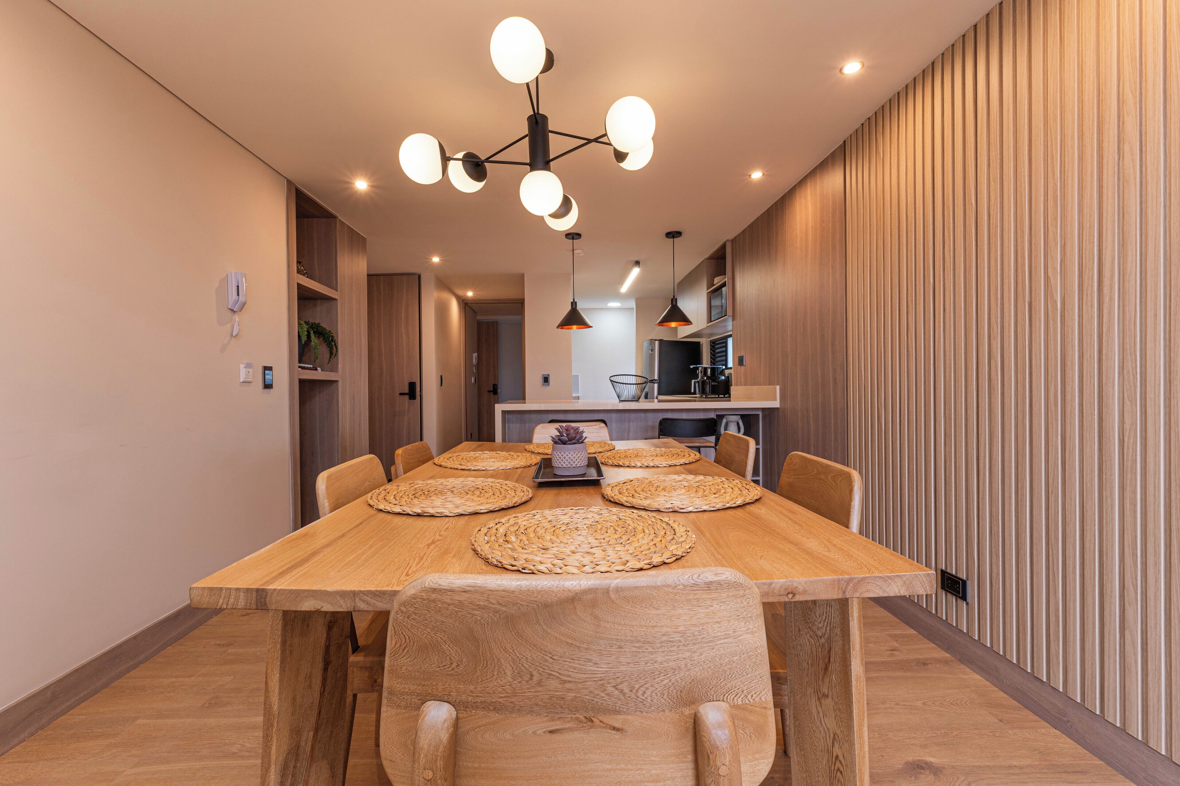 A dining area with a wooden table, woven placemats, and six chairs.