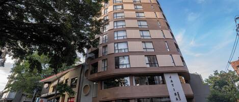 Un hotel de varios pisos con fachada curva, ventanas amplias y un letrero que anuncia un restaurante.