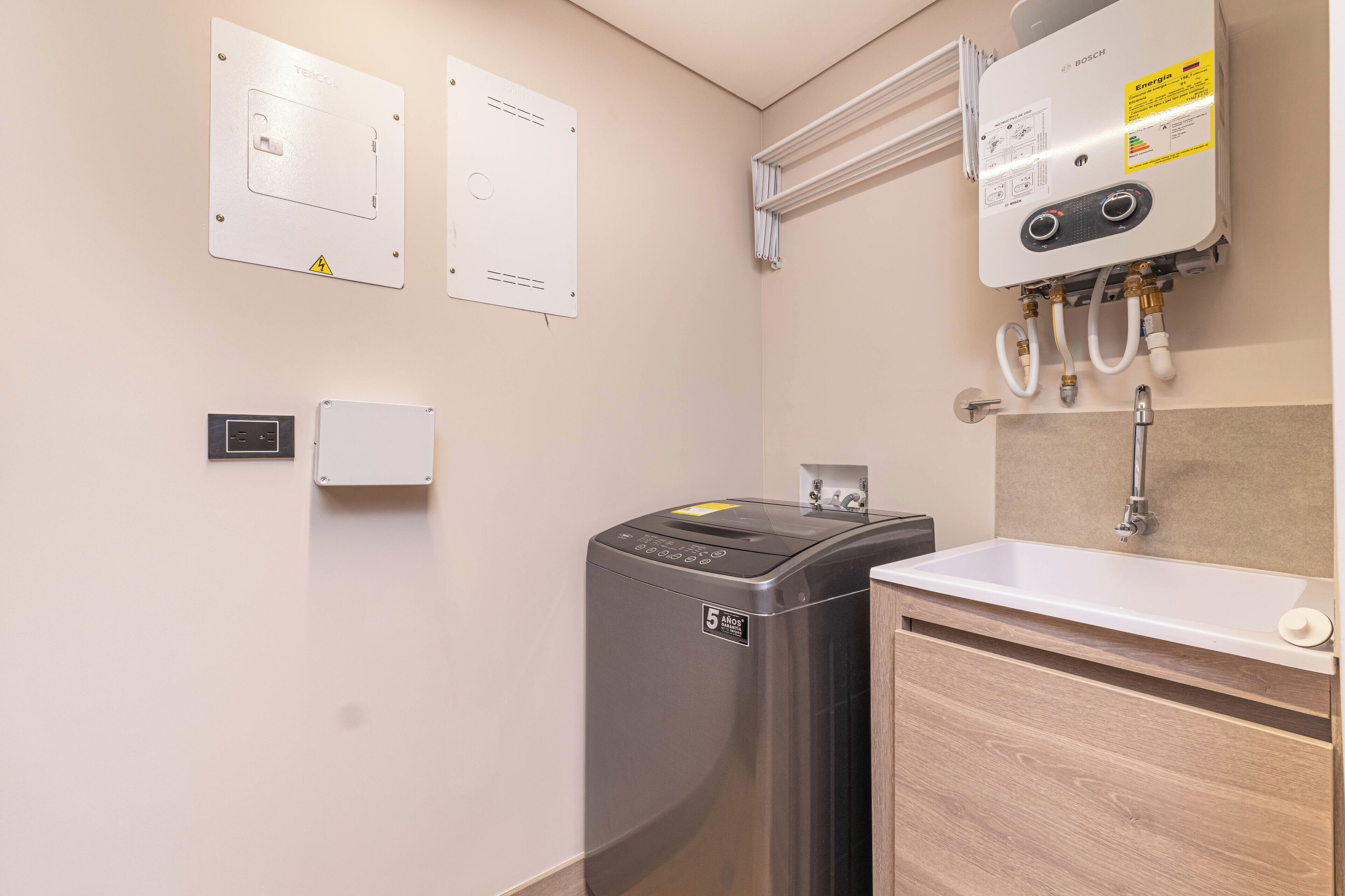 A bathroom with a Bosch washing machine, a sink, and a water heater.