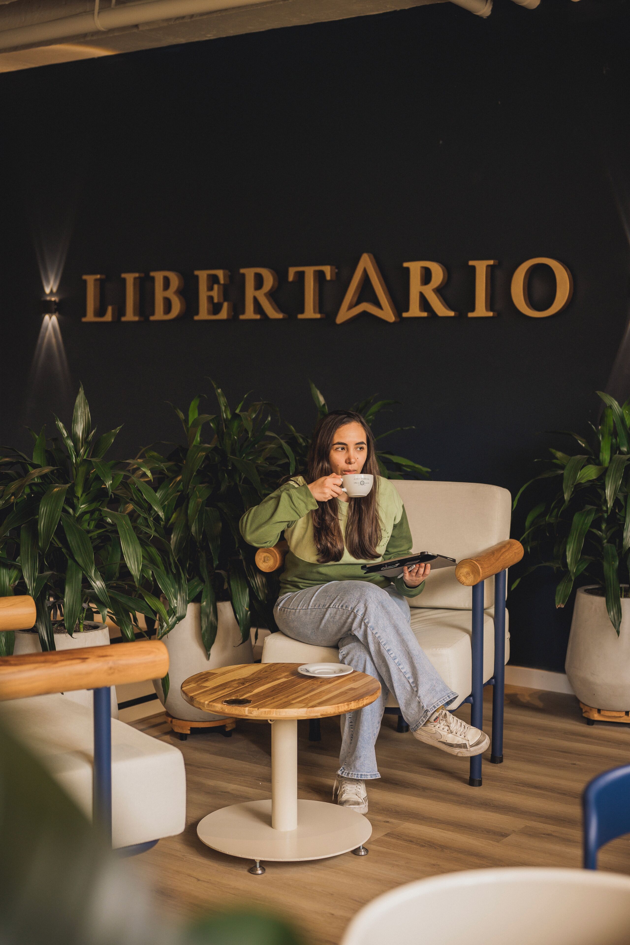Una persona sentada en una silla dentro de una habitación con un cartel que dice 'LIBERTARIO'.