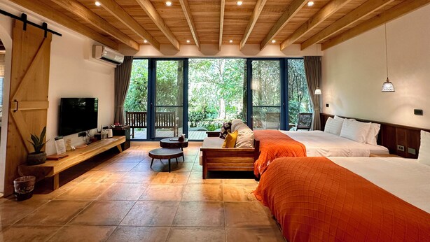 Een ruime slaapkamer met een groot bed, een klein bed, een televisie en een houten plafond.