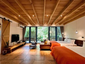 Un dormitorio amplio con una cama grande, una cama más pequeña, un televisor y techo de madera.