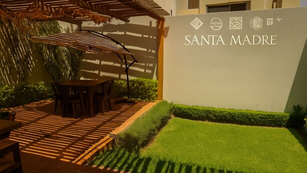 A patio area with a pergola, a table, and chairs, and a sign that reads "SANTA MADRE".