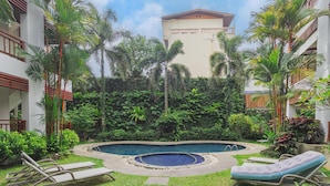 A pool area with lounge chairs, a circular hot tub, and lush greenery. - 1BR Condo Pool 5min Walk to Beach C131 (Choeng Thale)