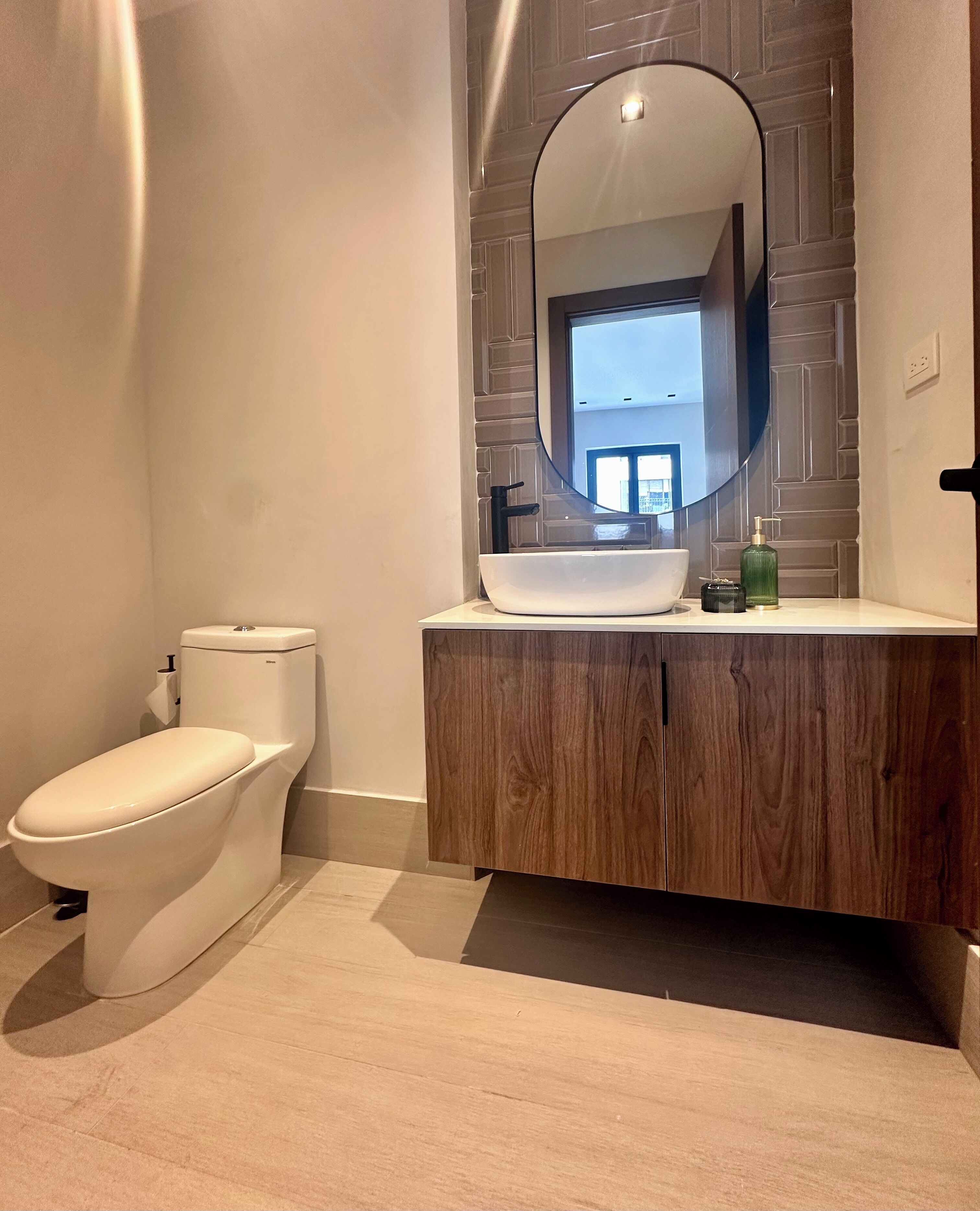 Een moderne badkamer met toilet, een wastafelmeubel met grote spiegel en een wastafel.