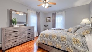 A bedroom with a bed, a dresser, a ceiling fan, and a window with curtains. - Historic Gettysburg Homestead for Large Groups (Gettysburg)