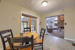 Un coin repas avec une table ronde et des chaises, une cheminée en arrière-plan et une vue sur le salon.