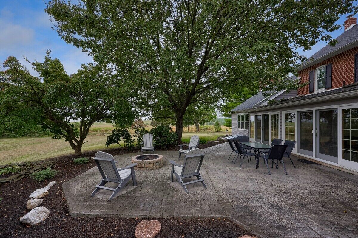 Une terrasse avec des fauteuils Adirondack, un foyer et une table.