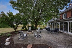 Une terrasse avec des fauteuils Adirondack, un foyer et une table.