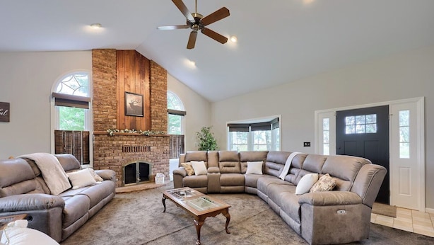 A spacious living room with a fireplace, leather sofas, a glass coffee table, and a ceiling fan. - Historic Gettysburg Homestead for Large Groups (Gettysburg)