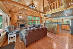 Ein Blockhaus-Interieur mit Wohnzimmer, Küche und Kamin aus Stein.