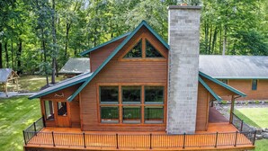 A wooden cabin with a balcony, a chimney, and a deck. - Forest Escape w/ Hot Tub & Bunk Rooms (Sturgis)