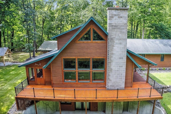 A wooden cabin with a balcony, a chimney, and a deck.