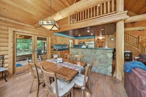 A log cabin interior with a dining area, kitchen, and stone accent wall.