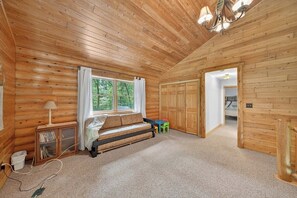 A log cabin interior with a wooden bench, a small table, and a window with curtains.