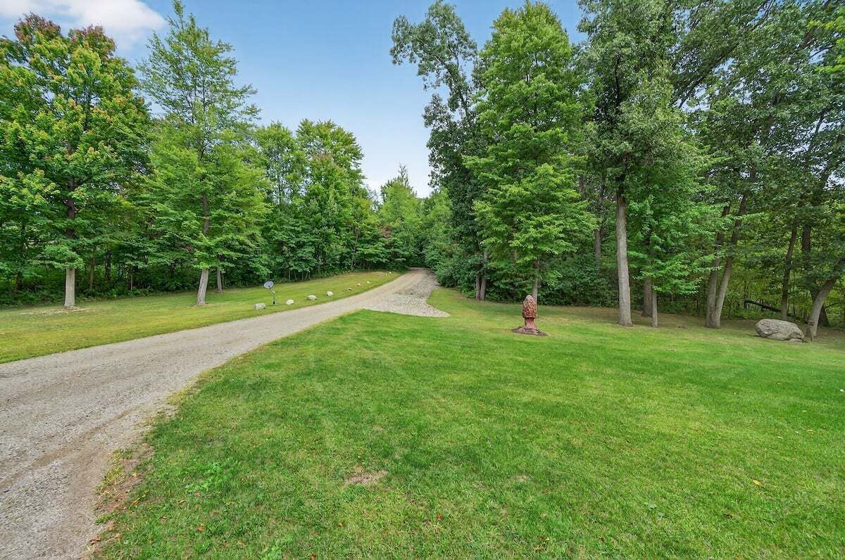 A gravel path leading through a grassy area with trees on both sides.
