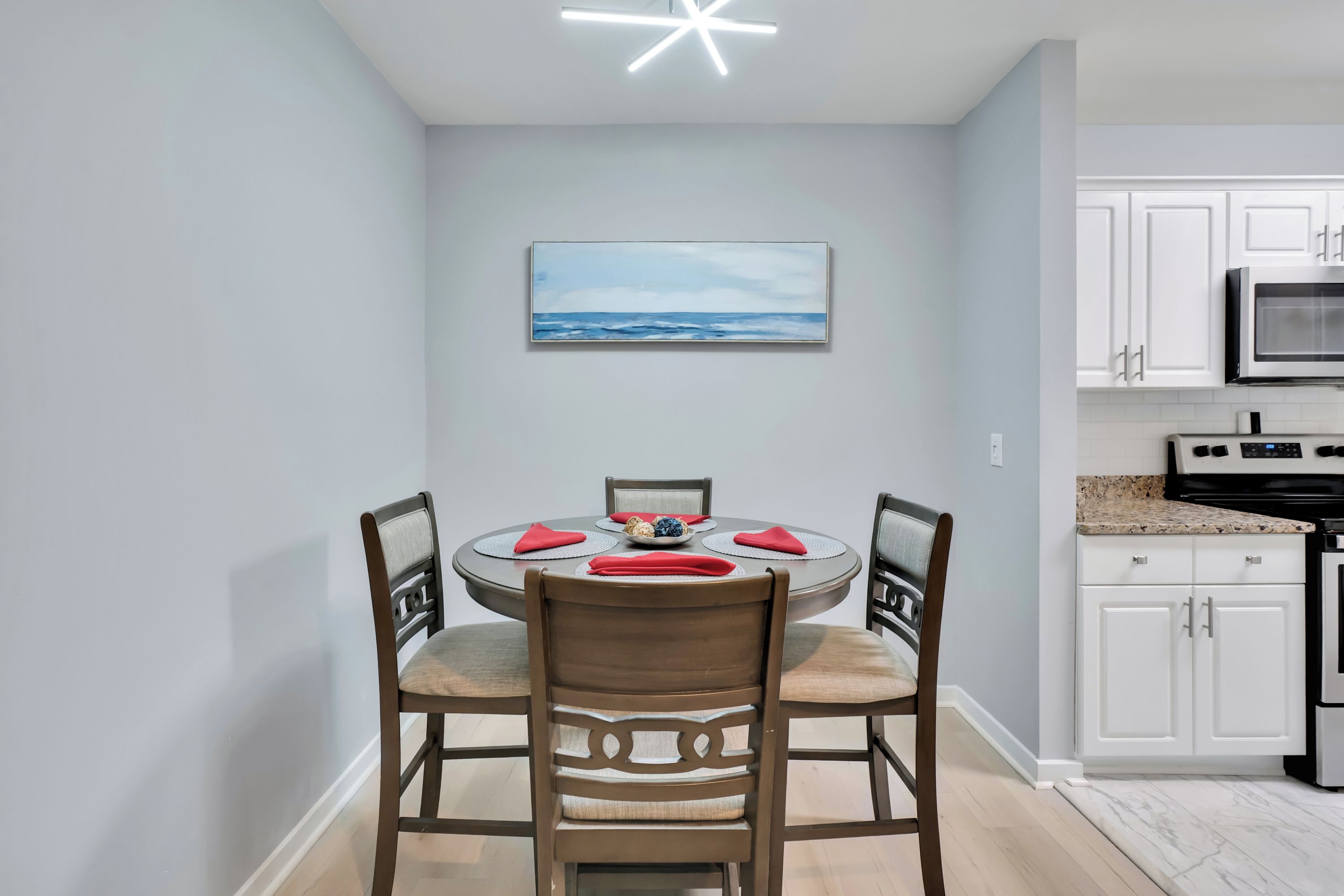 A modern kitchen with white cabinets, a granite countertop, and stainless steel appliances.
