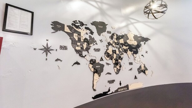 A world map wall decoration with a compass, a framed document, and a hanging light fixture. - King Room, Heart of Times Square (New York)
