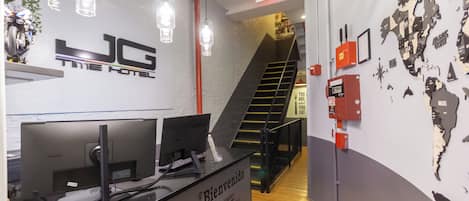 A reception desk with a computer, a world map on the wall, and a staircase in the background.