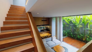 Un escalier moderne menant à une cuisine avec un coin repas et un petit jardin.