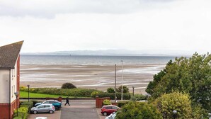 Ein Wohngebiet an der Küste mit Blick auf das Meer, parkenden Autos und einem Fußweg.