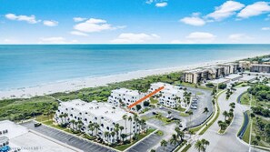 Ein Küstenhotel mit mehreren weißen Gebäuden, einem Parkplatz und einem Strand im Hintergrund.