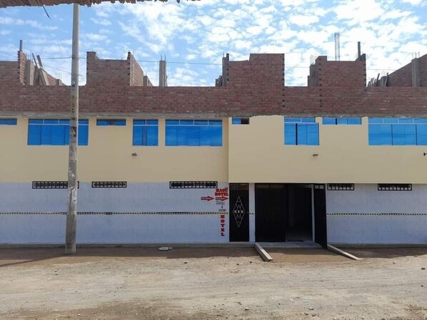 A two-story building with a ground-level entrance and a sign indicating a hotel. - Hotel magu huarmey (Huarmey)
