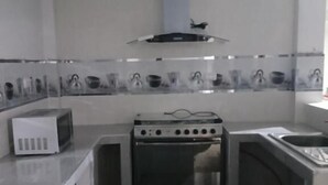Une cuisine compacte équipée d’un four à micro-ondes, d’une cuisinière, d’un four et d’un petit évier.