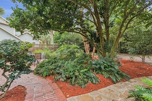 A landscaped garden with a variety of plants and a brick pathway.