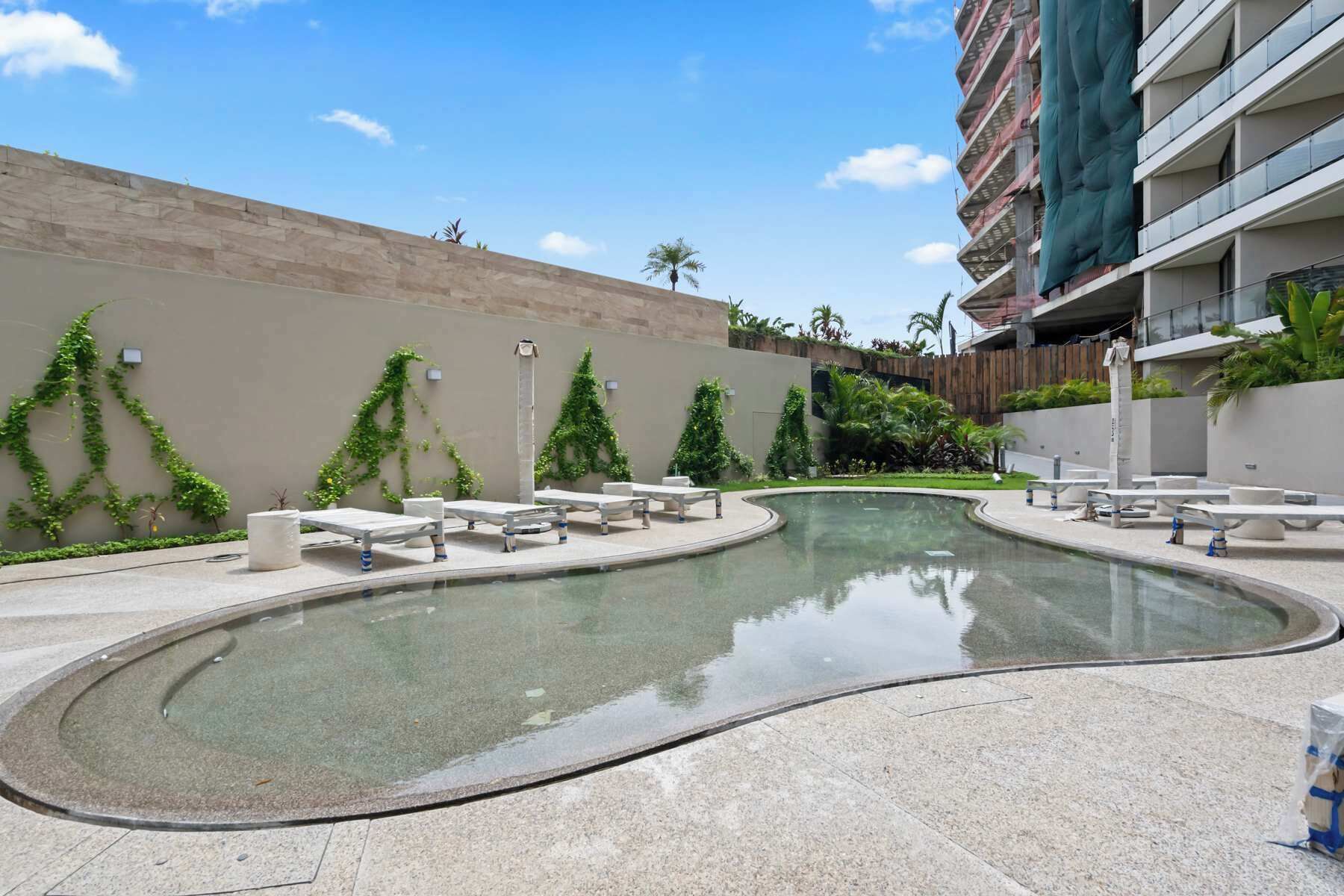 A swimming pool with lounge chairs and a stone wall.