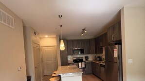 Una cocina moderna con una isla central, electrodomésticos de acero inoxidable y suelo de madera.