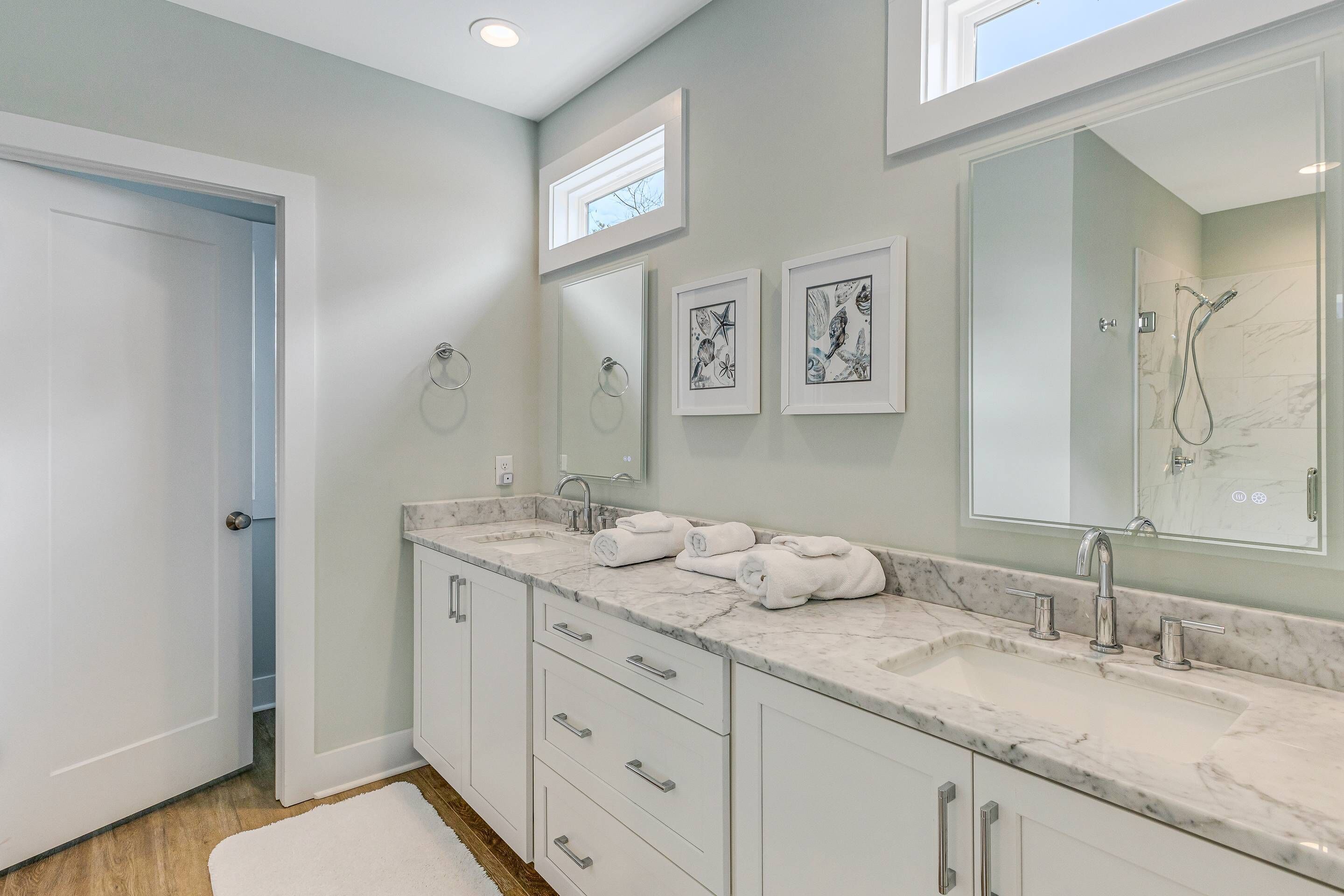 A modern bathroom with a large vanity, two sinks, and a walk-in shower.