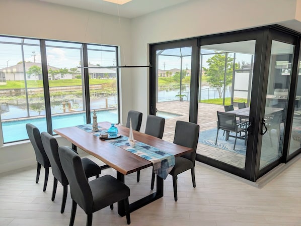 Comedor con vista a una piscina y un patio con mobiliario exterior.